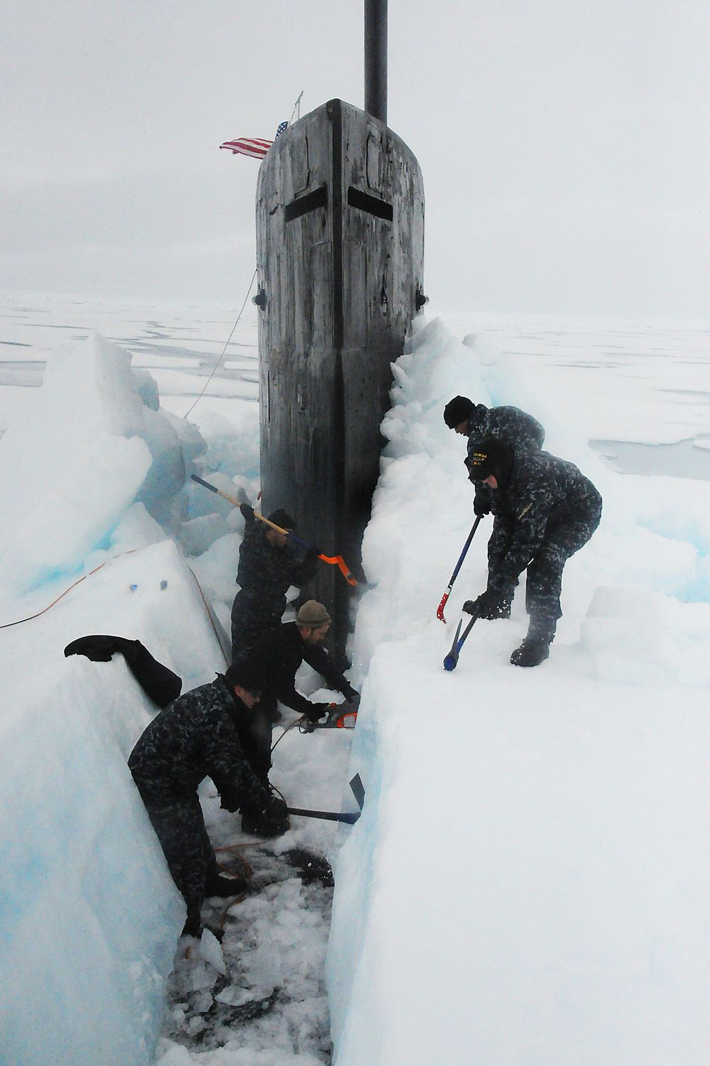 Isen har pakket seg rundt ubåten på Nordpolen. Mannskapet fjerner isen manuelt.  