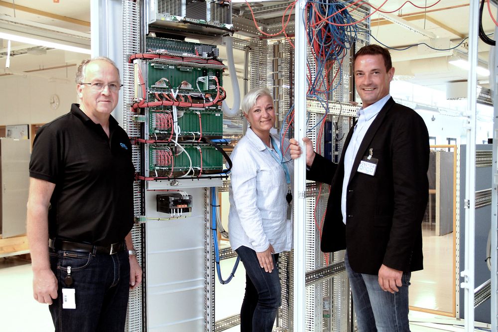 Fra venstre: Harald Albretsen, Monica Metzner fra Origo Solutions og Aron Øksdal fra CCS, her foran et skap under produksjon.