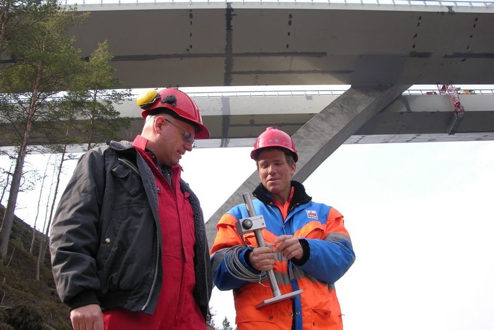 Instrumenteringsingeniørene Ole Petter Rotherud (t.v.) og Reto Tröndle med en av forskyvningsmålerne som skal monteres for å overvåke avstanden mellom bæresøylene og veidekket.