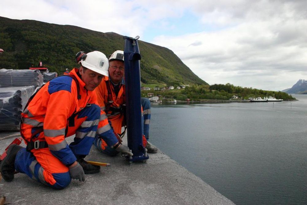 Øyvind Sunde (Nærmest) og Jarle Støyle i Tunnelteknikk monterer de siste rekkverkstøttene på Eiksdunbrua, med sikringsselen på.