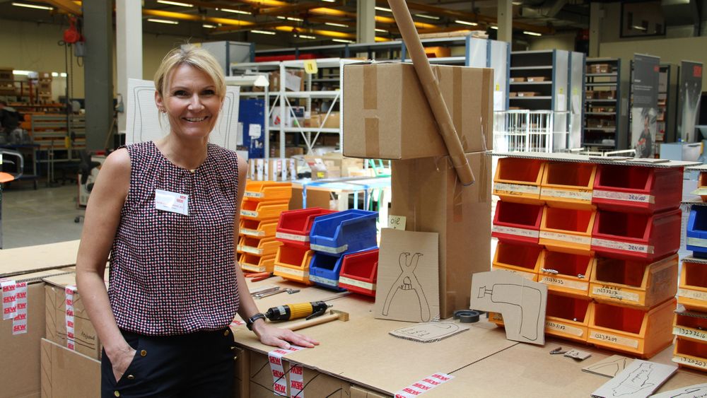 Heidi Svensen foran en arbeidsstasjon i kartong – som har dannet grunnlaget for bestilling av ny skreddersydd stasjon.