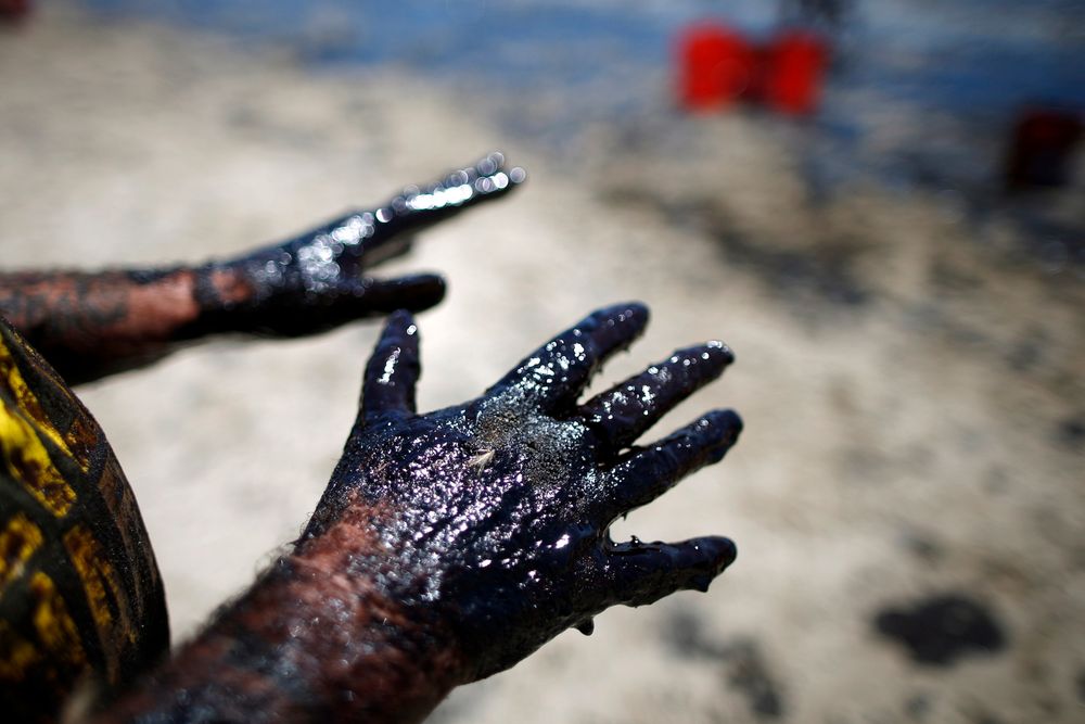 Full: Frivillige William McConnaughey (56) viser frem hender fulle av olje til fotografen. Han en er av mange som har meldt seg for å rydde opp etter oljeutsippet. 