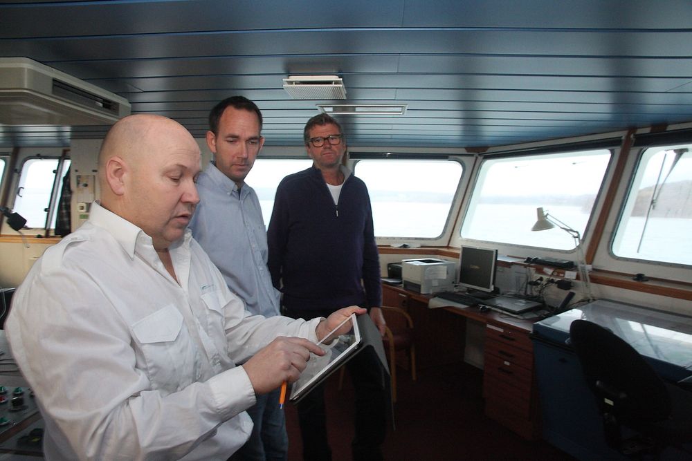 Kaptein Torleif Bakken på Bastø II med Rex ruteplanlegger på en iPad. Kaptein og sikkerhetsrådgiver Gisle Stava i Bastø Fosen har bidratt  til utviklingen av Rex som Geir Fagerhus (bakerst) i Marsec-XL står for. 