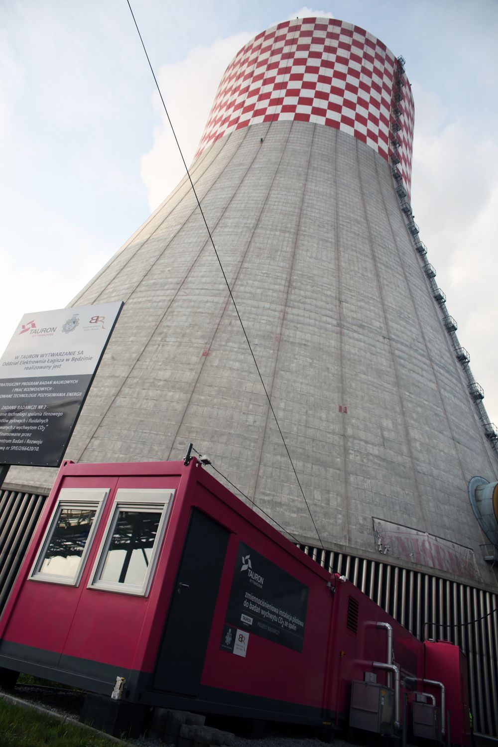 Containeren med det mobile CO2-rensingsanlegget blir liten ved siden av det 133 meter høye kjøletårnet på Lagisza-kraftverket.