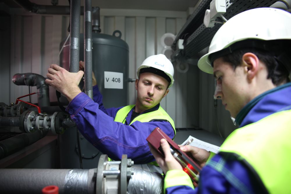 Sivilingeniørene Kamil Srokosz og Mateusz Kozak viser hvordan de kontrollerer at CO2-rensingen fungerer optimalt. Med en egen måler sjekker de hvor mye som renses.