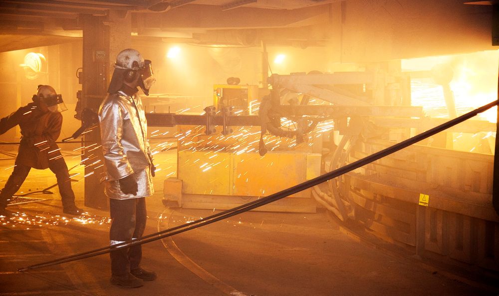 Arbeidere i flammehemmende drakter renser tappekanalene på den ombygde og miljøvennlige smelteovnen på Elkem Salten.