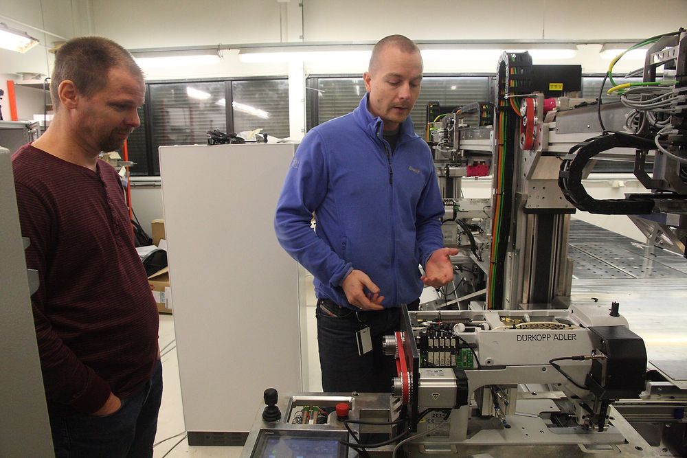 Ekornes og Amatec har jobbet med robotisering av symaskiner for møbelproduksjon. Bildet viser Terje Riksheim fra Amatec og Svein Even Blakstad fra Ekornes i abried med en protoyp i november 2014.