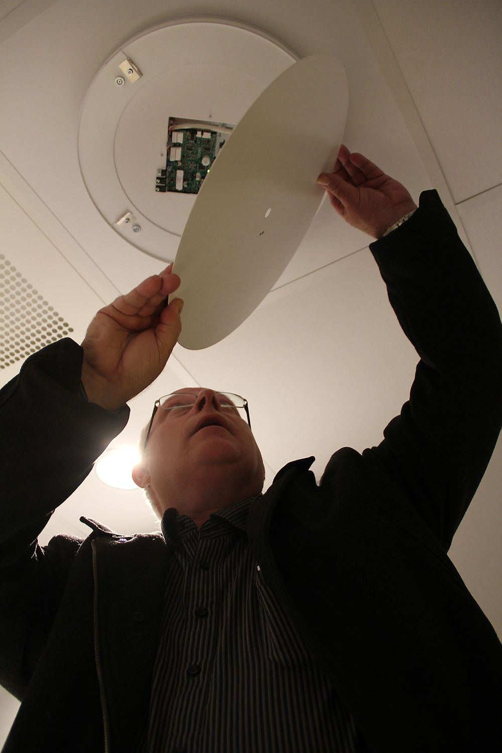Kjell Støkket sjekker en av de nye ventilene, med elektronikk og sensorer som styrer både ventilasjon og lys.