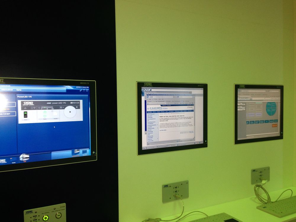 Tre til: I tillegg til de fem skjermene som omgir operasjonsbordet finner vi tre til på veggen som kan styre systemet og vise pasientdata.