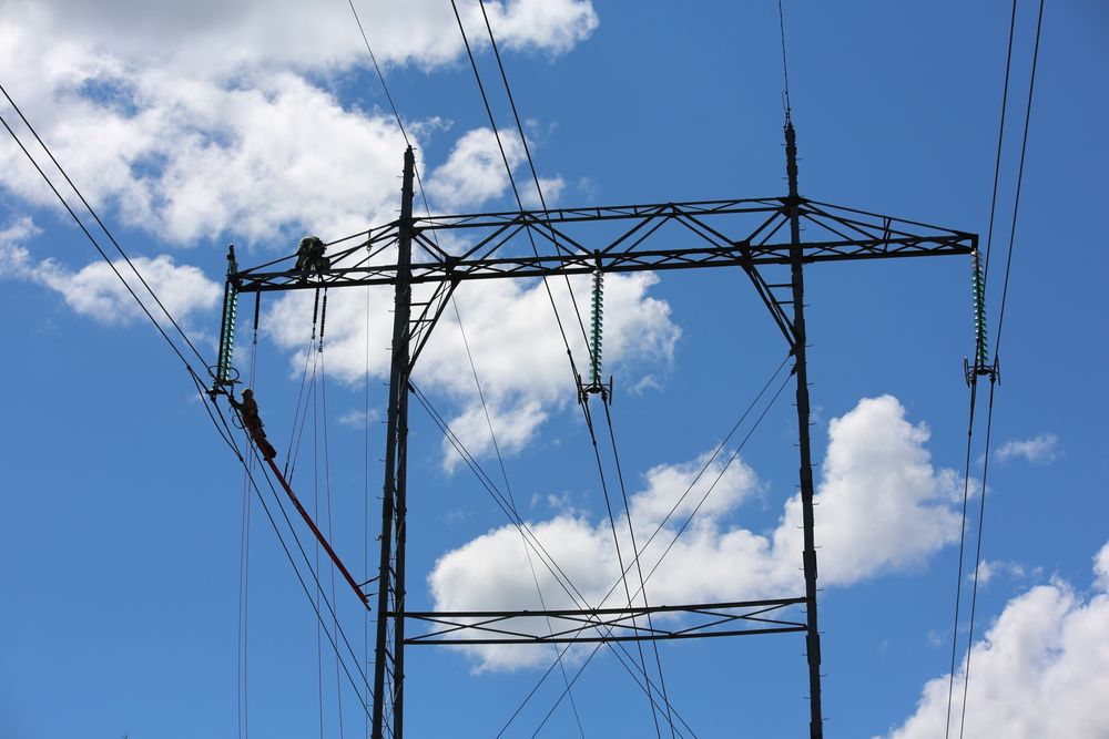 I toppen toppen av masta med spenningen på arbeider to menn for å oppgradere Statnetts kraftlinje fra 300 til 420 kV.