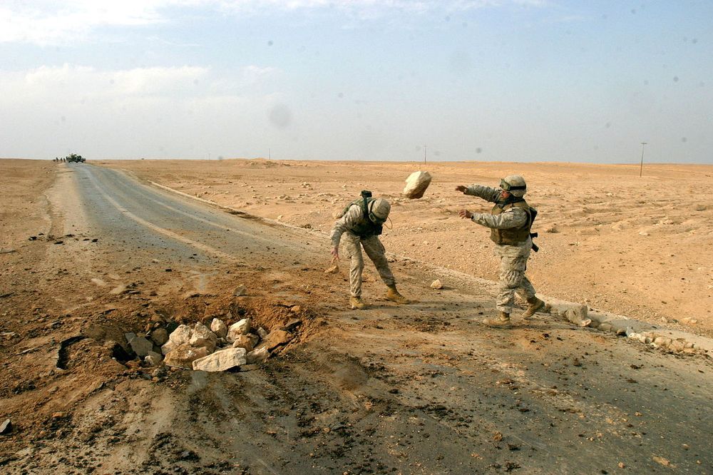 Soldater fra USAs marinekorps rydder opp etter en landmineeksplosjon på en vei i Al Qaim i Irak.