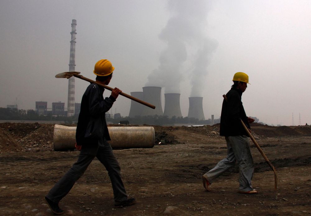 To arbeidere foran et kullkraftverk utenfor den kinesiske hovedstaden Beijing. Kullkraft er en av de viktigste kildene til utslipp av klimagassen CO2.