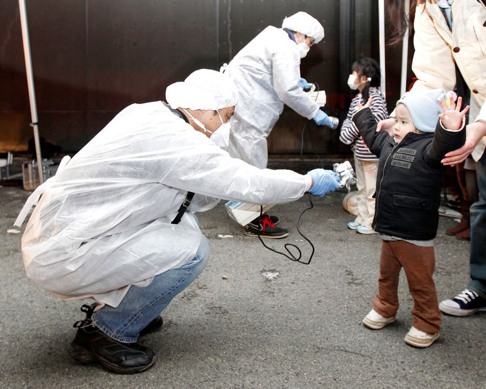 SJEKKES: Tjenestemenn i beskyttelsesutstyr leter etter spor av stråling på barn fra det evakuerte området nær kjernekraftverket Fukushima Daini i Koriyama.