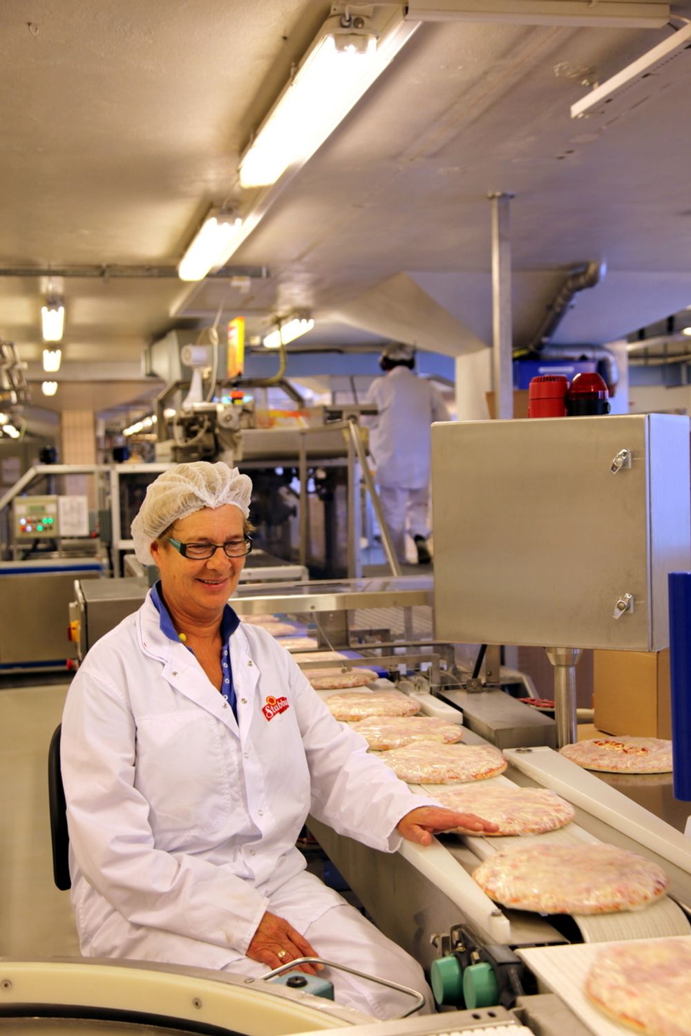 LANG FARTSTID: Eli Ødegård har vært med på pizzaeventyret i Stranda siden starten. Kontrollen av det ferdige produktet er erstattet av maskiner, men for sikkerhets skyld overvåkes hver eneste pizza også av en person.