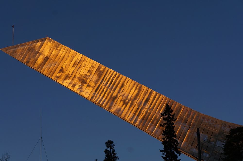 REFLEKSJON: Solen reflekteres i Holmenkollbakkens ovarrenn en klar kveld i Oktober.