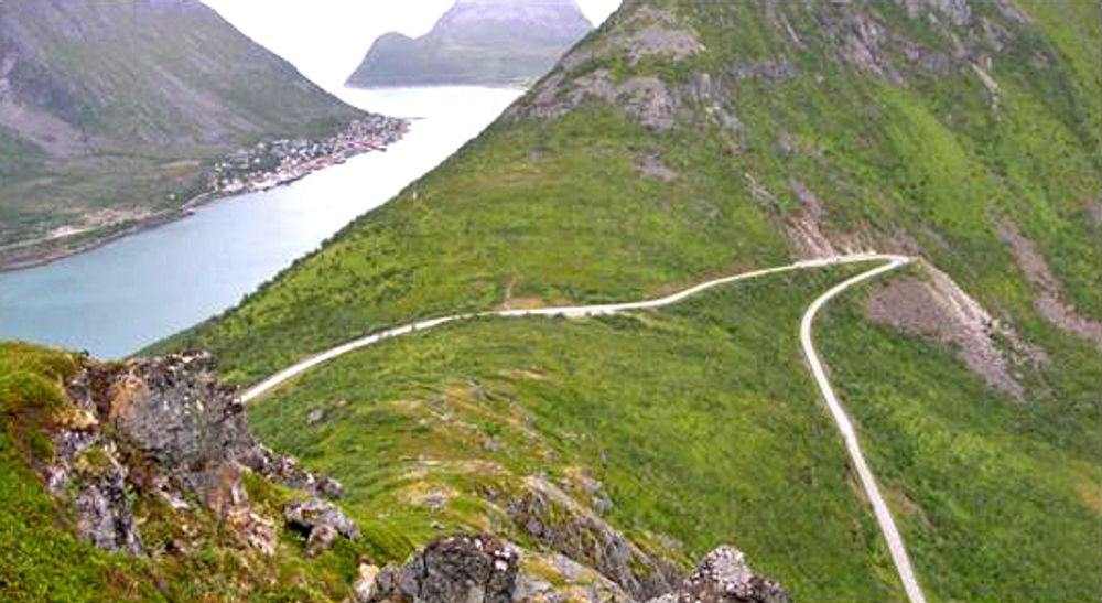 Bildet viser fylkesveg 86 over toppen av Ballesvikskaret. Fiskeværet Gryllefjord kan ses i bakgrunnen til høyre.