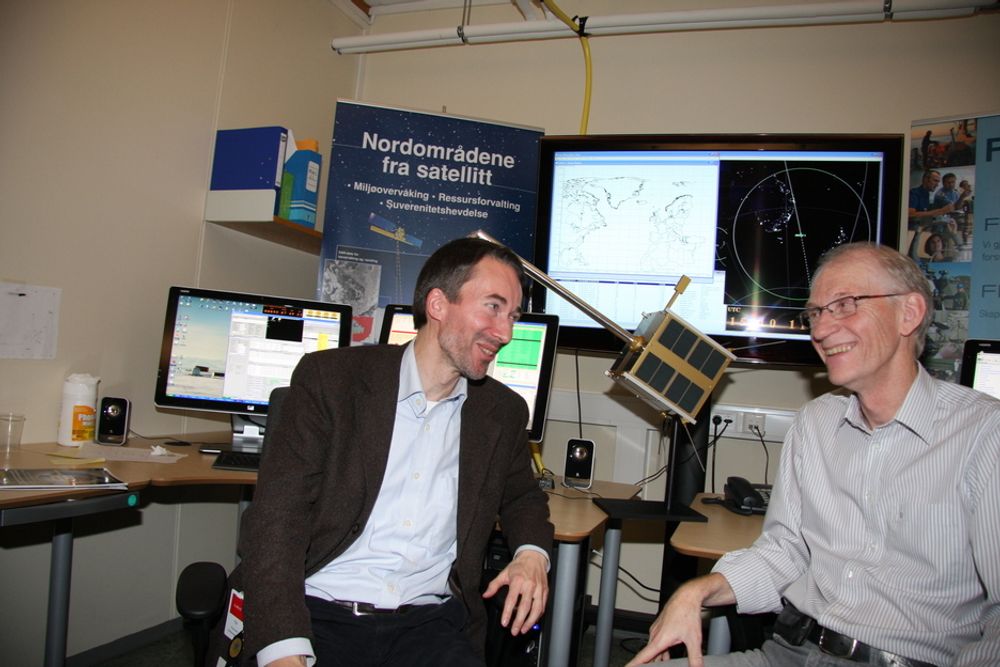 BEST: Bjørn Ottar Elseth (t.v.) fra Norsk Romsenter og Bjørn Narheim, sjefsforsker ved FFI og prosjektleder for AISsat-1, er stolte over å ha laget satellitten så lett og kompakt. Satellittkopien mellom dem er i størrelse 1:1.