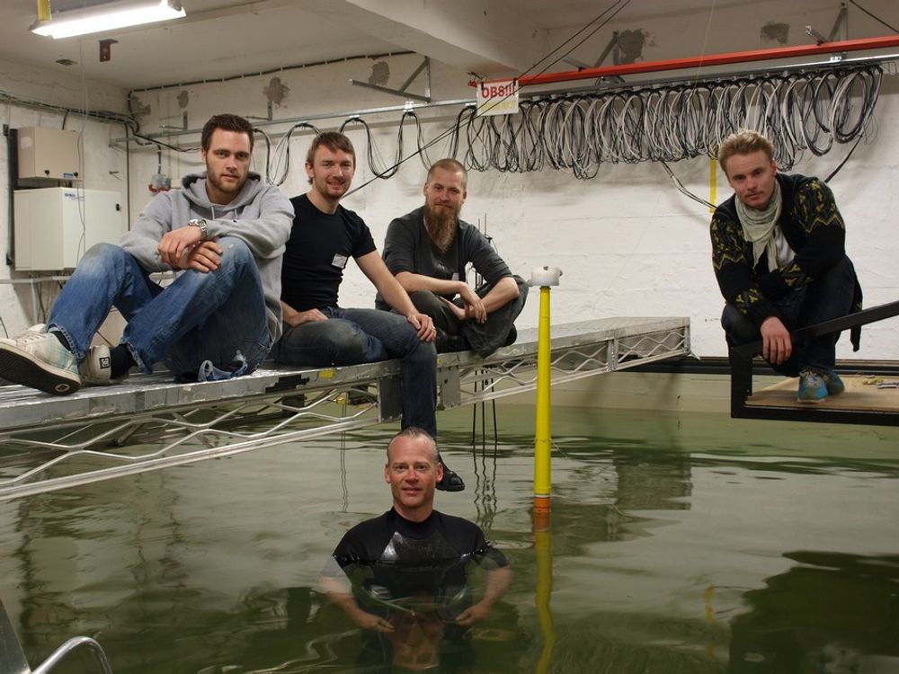 TESTES I VANNET: UMB-gruppen har testet ut den nye flytende vindturbinen i bølgebassenget til MARINTEK/SINTEF. Bak fra venstre: Fredrik Even Hansen, Anders Myhr, Karl Jacob Maus og Ulrik Aimar Møller. I vannet, ved Njord-modellen, er professor Tor Anders Nygaard.