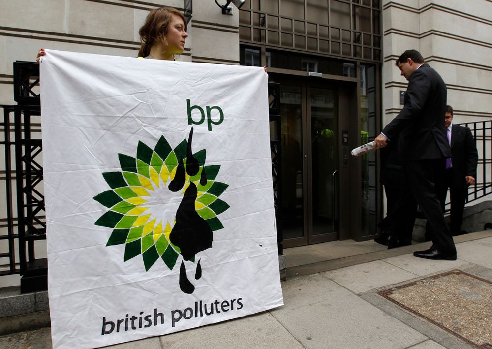En Greenpeace-aktivist holder opp en banner foran BPs hovedkontor i London torsdag.