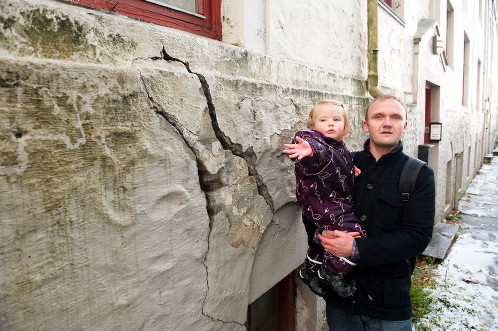 UTYGT: Heine Askeland og datteren Mia viser noen av sprekkene i muren i gården i Ladegårdsgaten i Bergen. Nærmere halvparten av beboerne er evakuert fordi bygården har fått store setningsskader og kan være farlig å bo i.