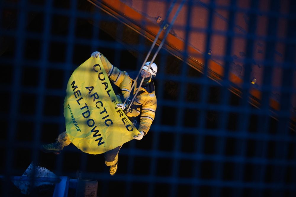 KRAFTANSTRENGELSE: En Greenpeace-aktivist klatrer i kranen som laster kull fra Sveagruven på Svalbard ombord i skip. Plakaten sier "Coal Fired Arctic Meltdown".