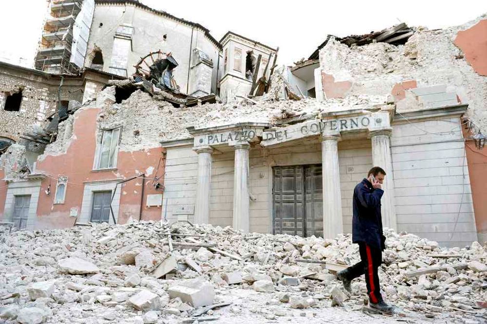 RASERT: En italiensk politimann går forbi ett av husene som raste sammen under nattens jordskjelv. Mange er drept fordi husene deres raste sammen.