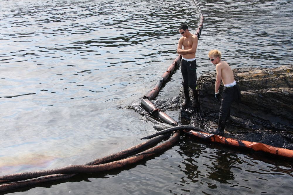 Mannskap fra Veolia Miljø suger opp olje i Krogshavn ved Langesund. Bilde tatt rett etter ulykken 31. juli i fjor.