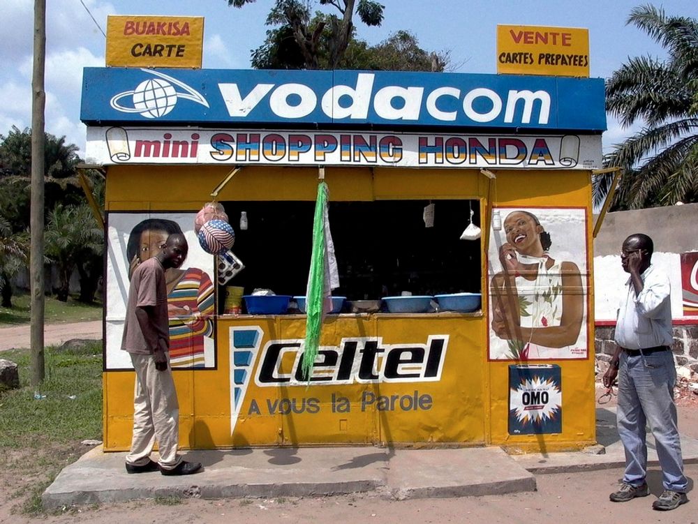 To menn står utenfor en kiosk som selger mobiltelefonkort i Kongos hovedstad Kinshasa. Mobiltelefonrevolusjonen i Afrika har enorme positive ringvirkninger for kontinentet både økonomisk, sosialt og politisk.