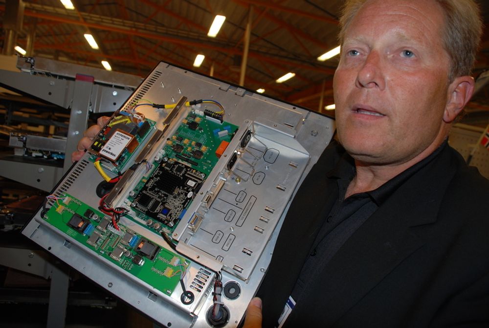 EFFEKTIV LAGERHJELP: Direktør Knut Vidar Lauritsen i Hatteland Display viser innmaten til en dataskjerm som bedriften produserer. Delene lagres i en Autostore-innretning som står i enden av fabrikklokalet på Nedre Vats.