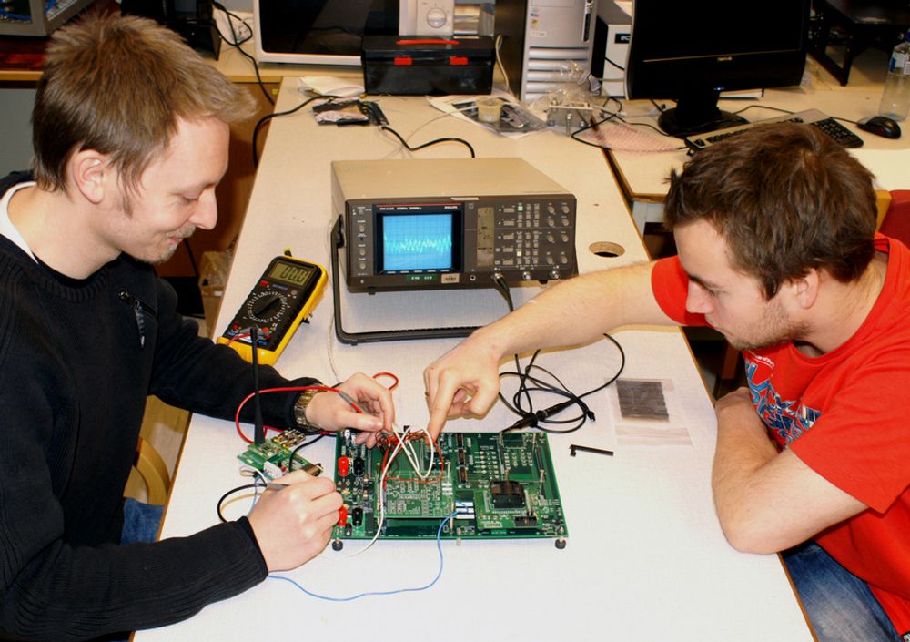 Romteknologistudentene Espen Oland (til høyre) og Lasse Ulvær jobber med testbrettet til Høgskolen i Narviks nye satellitt HiNCube.