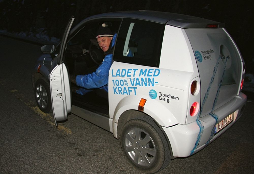 Eltaxieier og sjåfør Arne Asphjell sparer strøm og kjører i varmedress og lue.