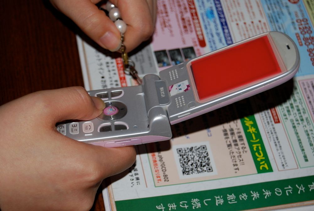 HJELP Å FÅ: Slik ser den spesielle koden ut. Fotografer koden med mobilen og dermed blir du loset fram til rett nettside. Maskeringen på mobilen er for å hindre innsyn fra andre japanere.