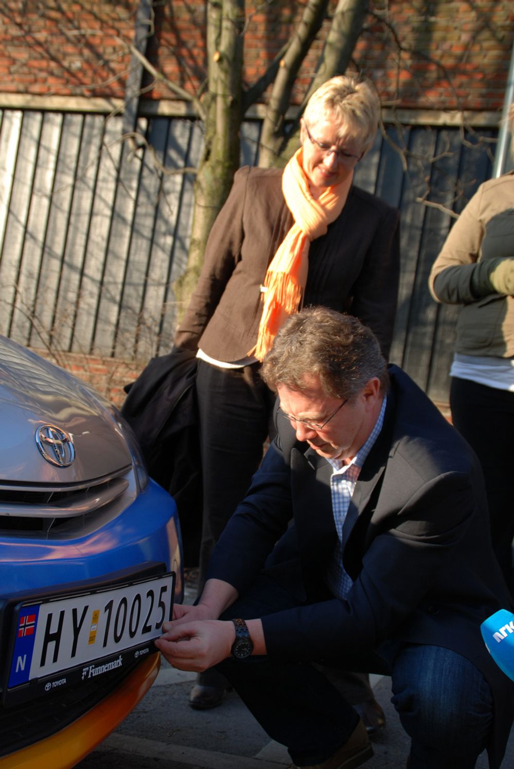 FØRSTE FESTE: Daglig leder i Miljøbil Grenland, Bjørn Nenseth, fester det første skiltet, mens samferdselsministeren følger med.