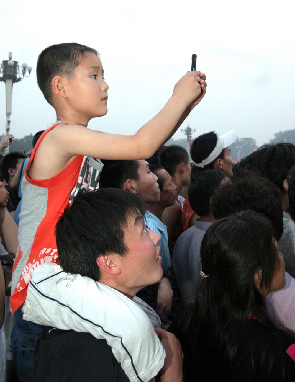 INGEN ER FOR LITEN: Årsaken til at mobilbruken har tatt så av i Kina er at operatørene tilbyr såkalt "1-kroners telefoner". Mange kinesere, slik som denne gutten og hans far, har ikke internett hjemme. men får internettilgang via mobilen. Men dette er sterkt sensurert av myndighetene.