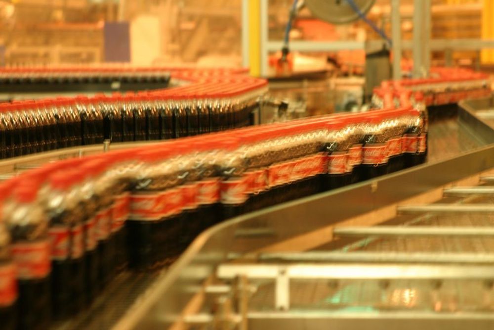 STOR KAPASITET: Her dundrer tusenvis av halvlitere med Cola på samlebåndet - til sammen 100 000 kasser brus i døgnet.