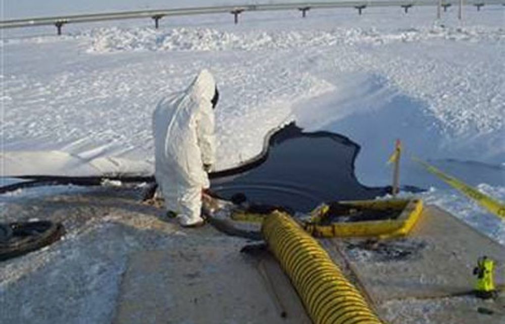 En arbeider prøver å suge opp olje og smeltet snø fra den alvorlige oljelekkasjen på rørledningen gjennom Alaska