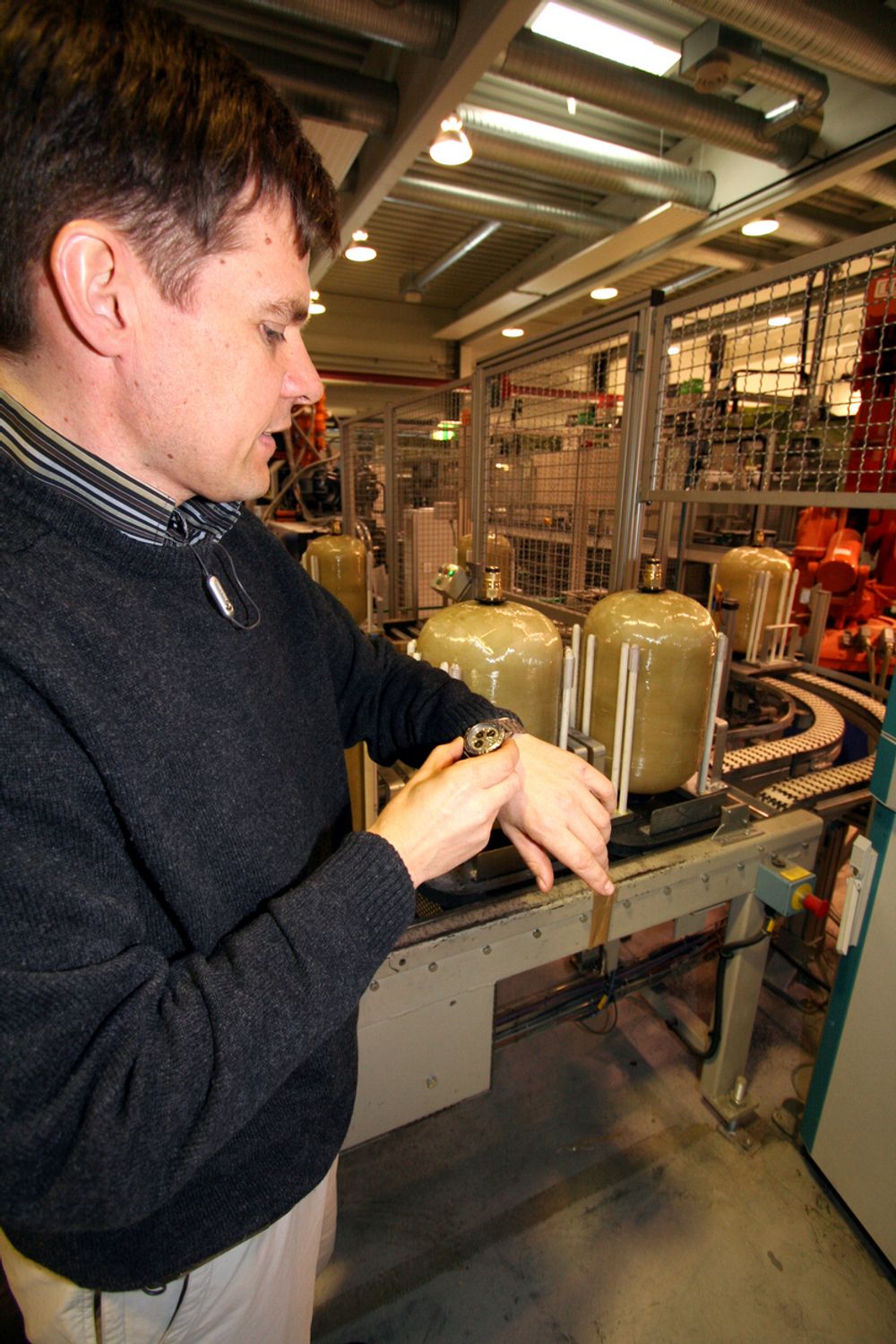 SJEKKER TIDA: Fabrikksjef Skjalg Stavheim konstaterer at gassbeholderen ikke blir heftet noe sted. Hvert 35. sekund settes en ferdig gassflaske på pallen - robotene har halvert produksjonstida i fabrikken.
