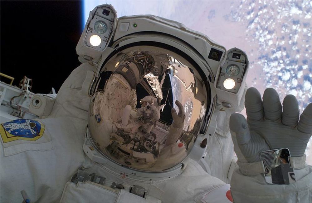 Den japanske astronauten Soichi Noguchi vinker til den amerikanske astronauten Stephen K. Robinson på deres første av tre spaserturer ut i rommet (spacewalks).