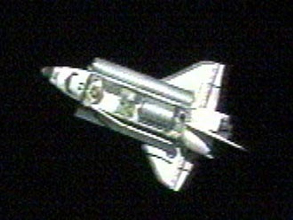 Discovery fotografert fra ISS. Lukene til lasterommet åpnes og bommen med den ekstra armen for å inspiserer romferga utvendig, monteres.