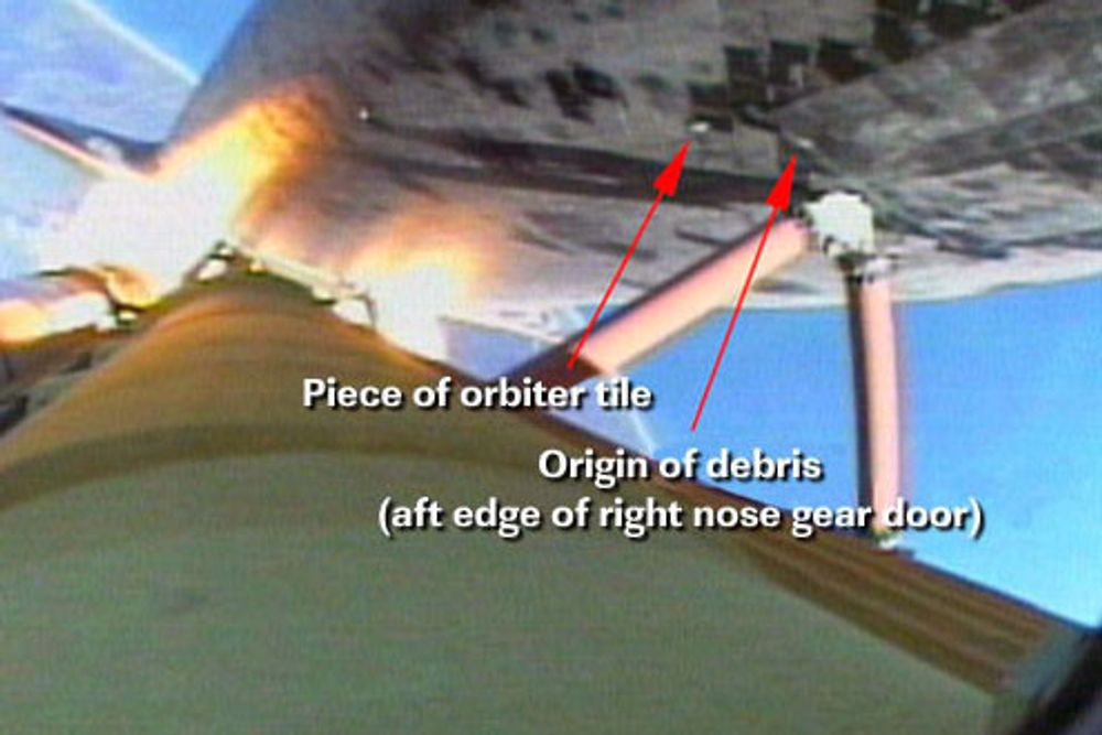 En bit på ca. 4 centimeter faller av fra undersiden av Discovery, 65 sekunder etter start. Det er antakelig en del av en flis rett ved hjulbrønnen for landingsunderstellet.