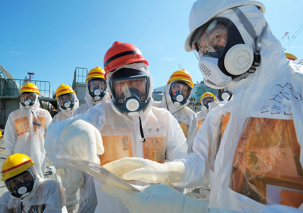 Japans minister for økonomi, handel og industri, Toshimitsu Motegi (i midten), besøker det ulykkesrammede atomkraftverket Fukushima Daiichi ikledd beskyttelsesklær og maske. Målinger har den siste tida avslørt store lekkasjer av radioaktivitet ved kraftverket. 