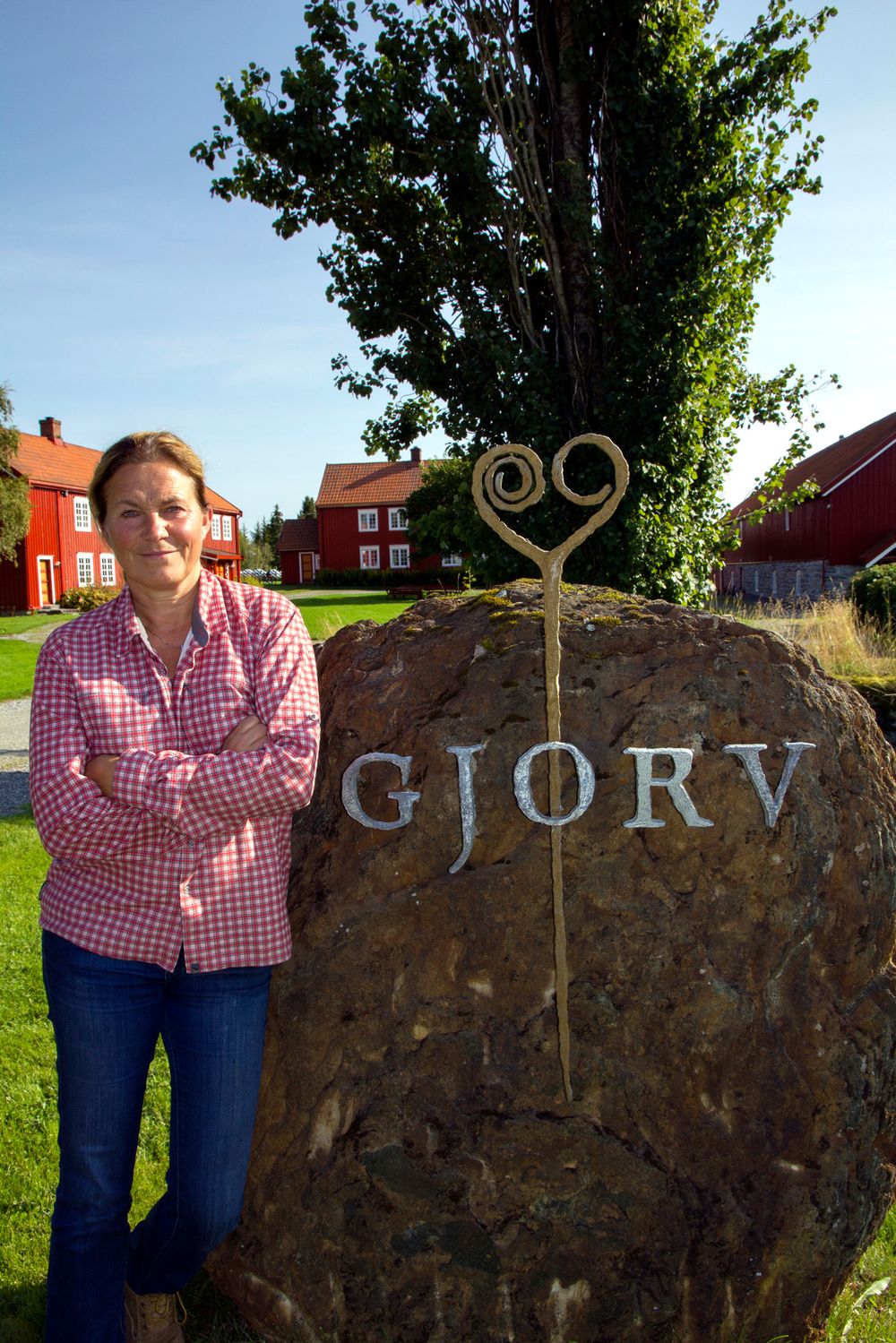 Bronsenål: Alexandra Bech Gjørv ved steinen og nåla som er blitt logo for gården. Det er gjort flere funn fra bronsealderen som viser at det har bodd folk på gården i 3000 år. 