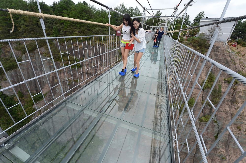 Småredde turister beveger seg over glassbrua. 