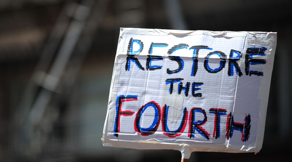 A protester holds a sign asking to restore the fourth after recent information has unearthed a web of NSA spy programs