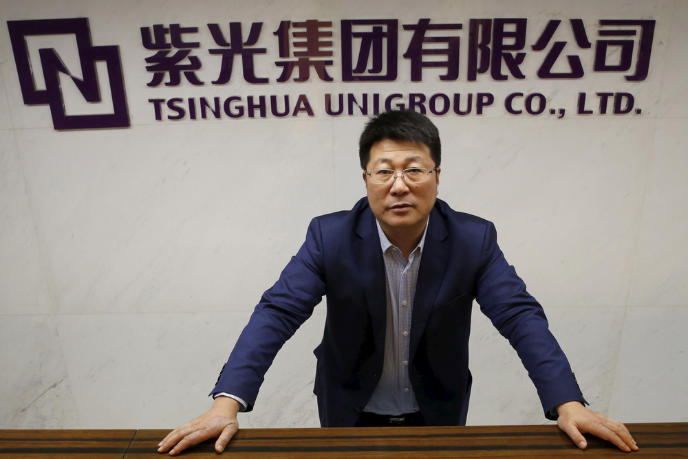 Styreformann Zhao i Tsinghua Unigroup poserer foran selskapets logo under søndagens intervju med Reuters i Beijing. Teknologiselskapet springer ut fra eliteuniversitetet med samme navn, der blant annet Kinas president Xi Jinping har sin utdannelse fra.