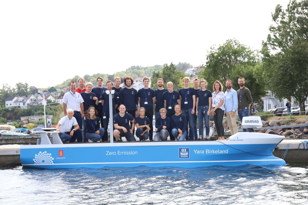 Studentprosjekt Kongsberg Maritime/FFI 2018: Smartship. De 16 studentene og veiledere og prosjektledere fra Kongsberg Maritime foran modellen de har utstyrt og testet. 