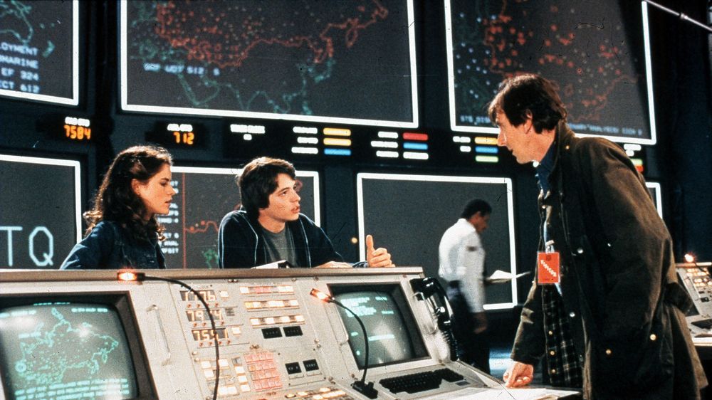 Scene fra WarGames-filmen med skuespillerne Ally Sheedy, Mathew Broderick og John Wood. I bakgrunnen sees noen av de store skjermene til WOPR-datamaskinen til NORAD.
