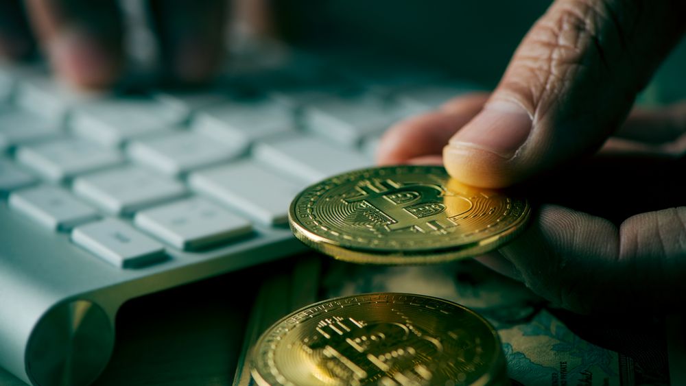 closeup of a young man having a bitcoin from a pile of bitcoins while is using a computer, with a dramatic effect