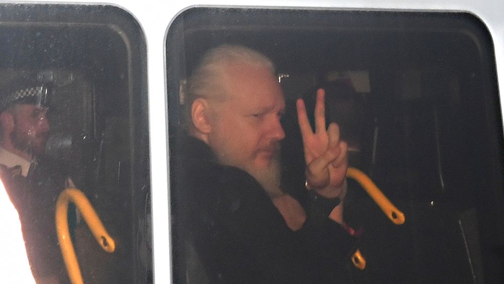 Julian Assange gjør en gest fra bilen hvor han føres bort etter pågripelsen torsdag. 