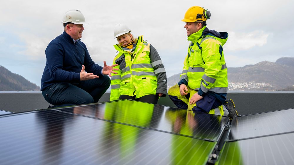 Prosjektleder Tomas Plassen (f.v.) og daglig leder Marie Therese Heldal Haukeland i Heldal Eiendom diskuterer solcellepanelene på taket av bygget på Slettebakken med Kjetil Strand Solheim, prosjektansvarlig og byggeleder i BKK. 